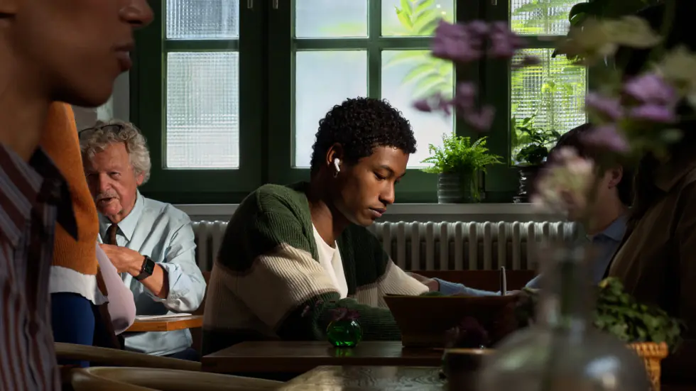 A person wearing AirPods 5, focused in a busy café