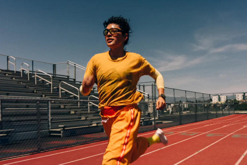A person running on an athletics track, wearing Apple Watch